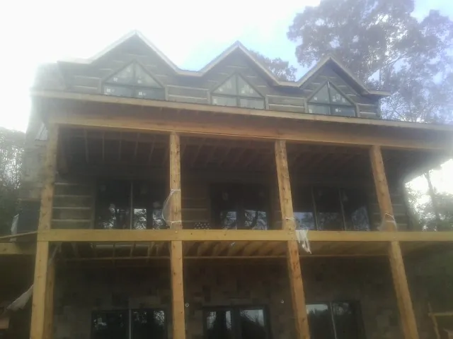 Dormers and porch framing on a large log home under construction — Roof Coating work by our crew in Gallatin