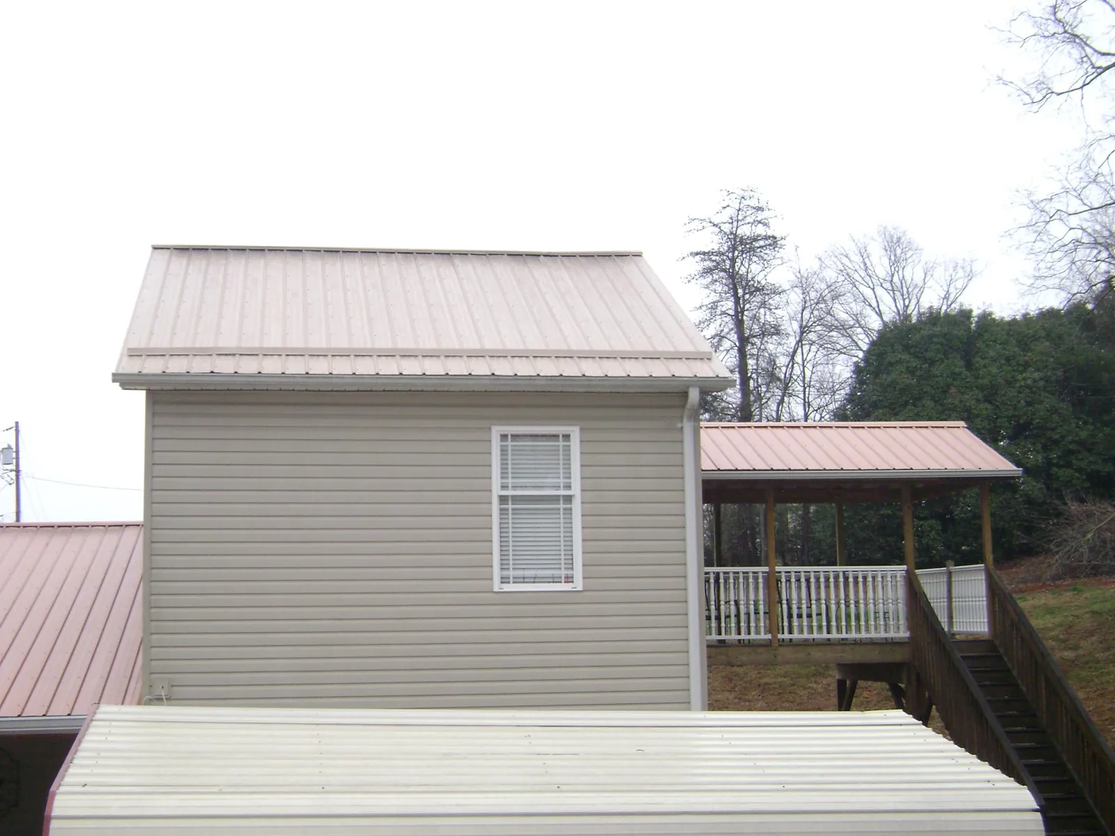 Tan metal roofs on a two story addition and attached porch, from a Roof Replacement job in Gallatin