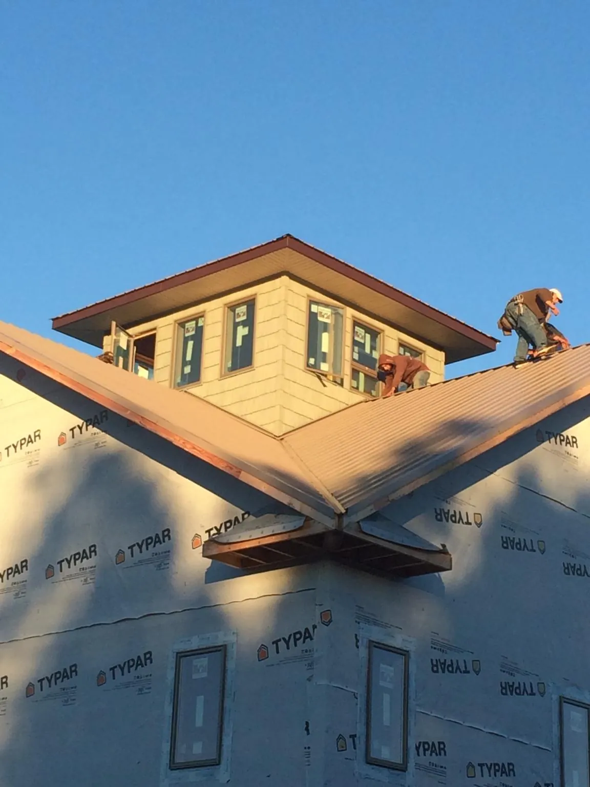 Roofers working around a rooftop cupola on a new metal roof at sunset — Roof Waterproofing in Gallatin by Roofing Brothers